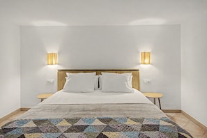 Ein Hotelzimmer mit einem Bett, zwei Nachttischen, einem Holz-Kopfteil und zwei Wandlampen.