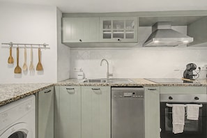 Eine Küche mit Waschmaschine, Geschirrspüler, Backofen und Kaffeemaschine.