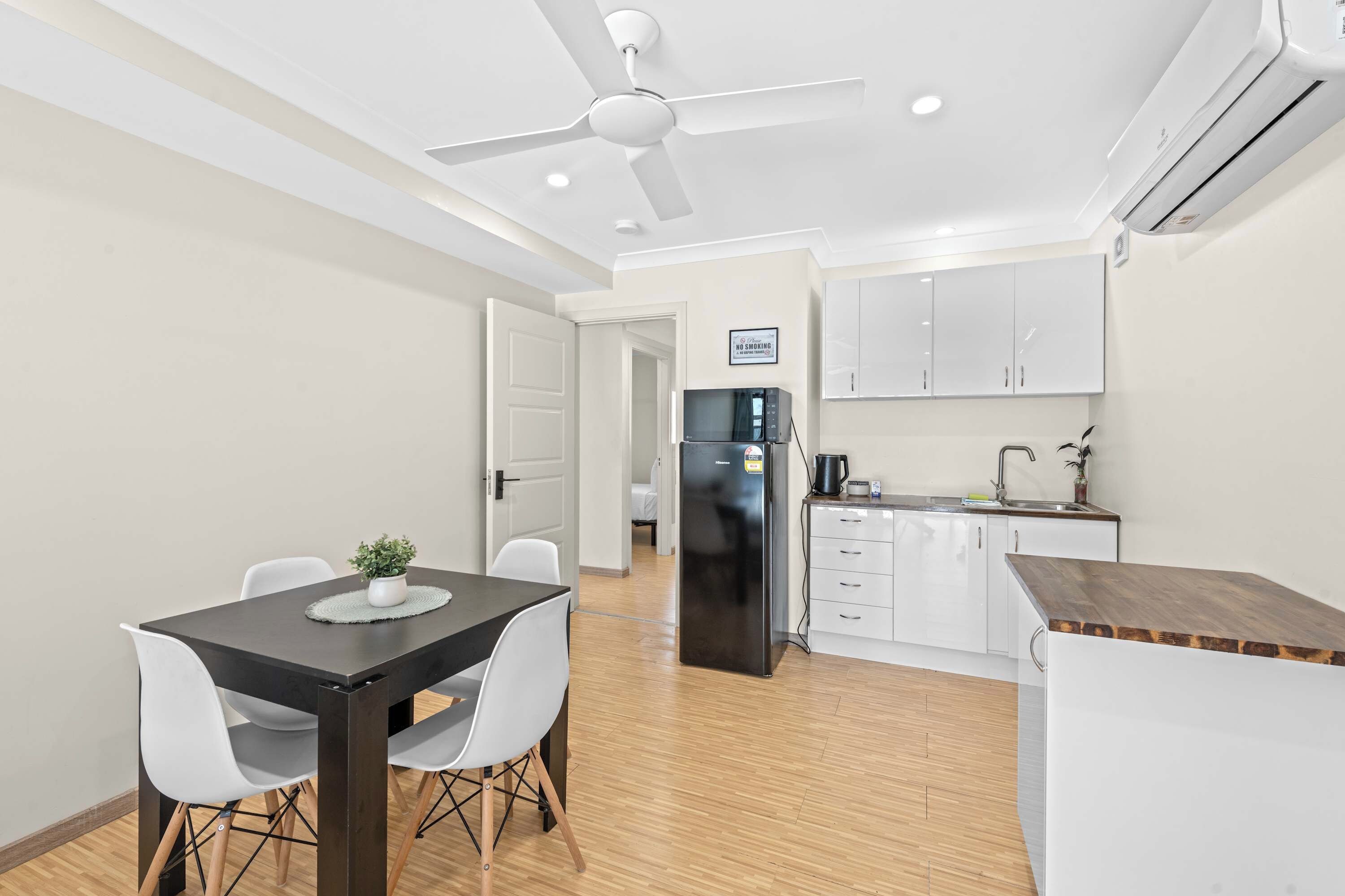 A modern kitchen with white cabinets, a black refrigerator, and a dining area with a table and chairs.