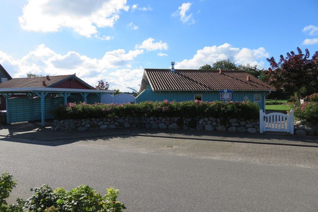A residential property with a stone wall, a blue house, and a white picket fence.