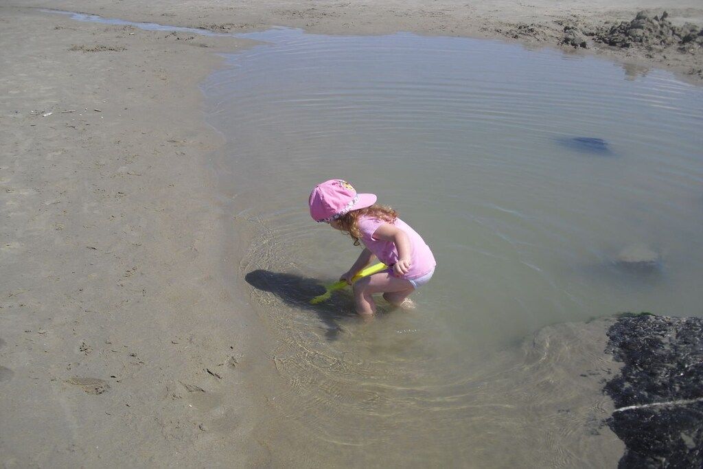 Un bambino gioca in acque basse su una spiaggia.