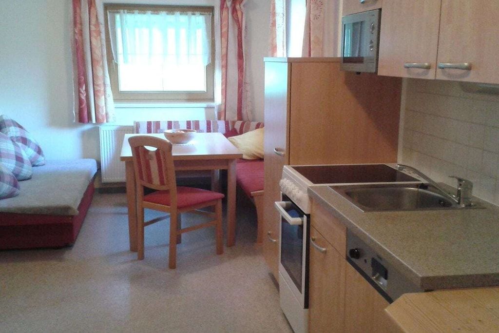 A compact kitchen with a dining table, chairs, a microwave, and a sink.