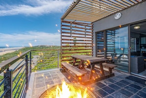 A balcony with a fire pit, outdoor seating, and a view of the beach. - "Serene Shores" Ocean View Luxury in Durban, South Africa (Kingsburgh)