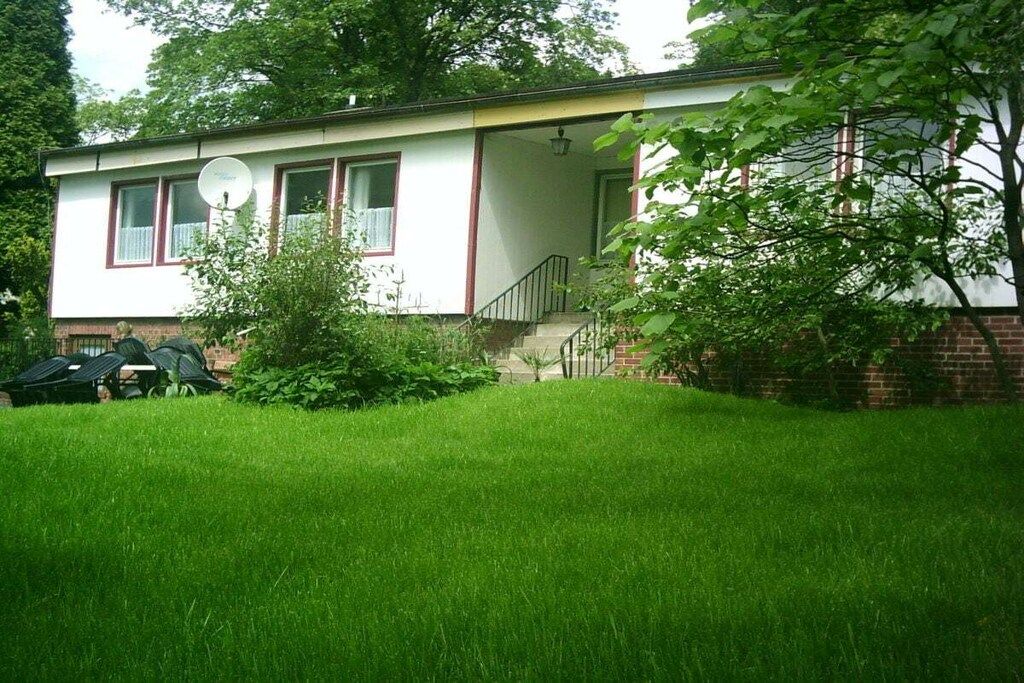 A single-story house with a front porch, a small staircase, and a brick foundation.
