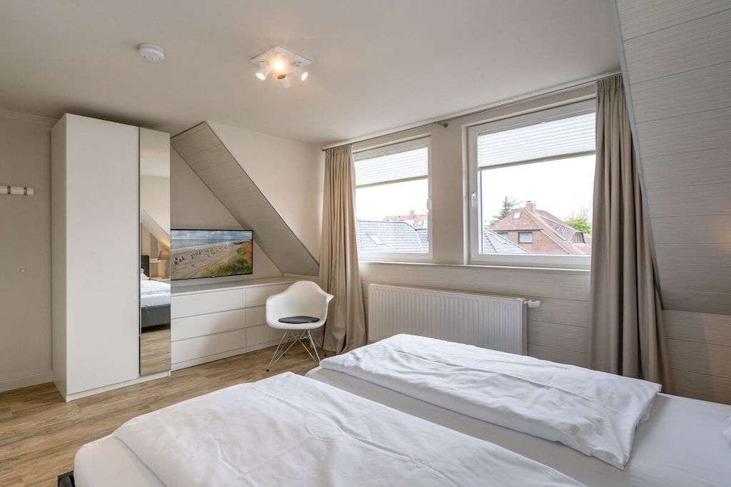 A bedroom with a bed, a desk, a chair, and a window.