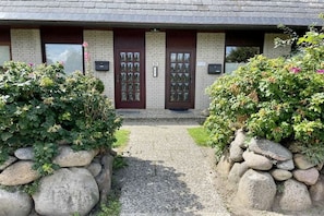 A building with two symmetrical doors, a stone pathway leading to the entrance, and a brick facade.
