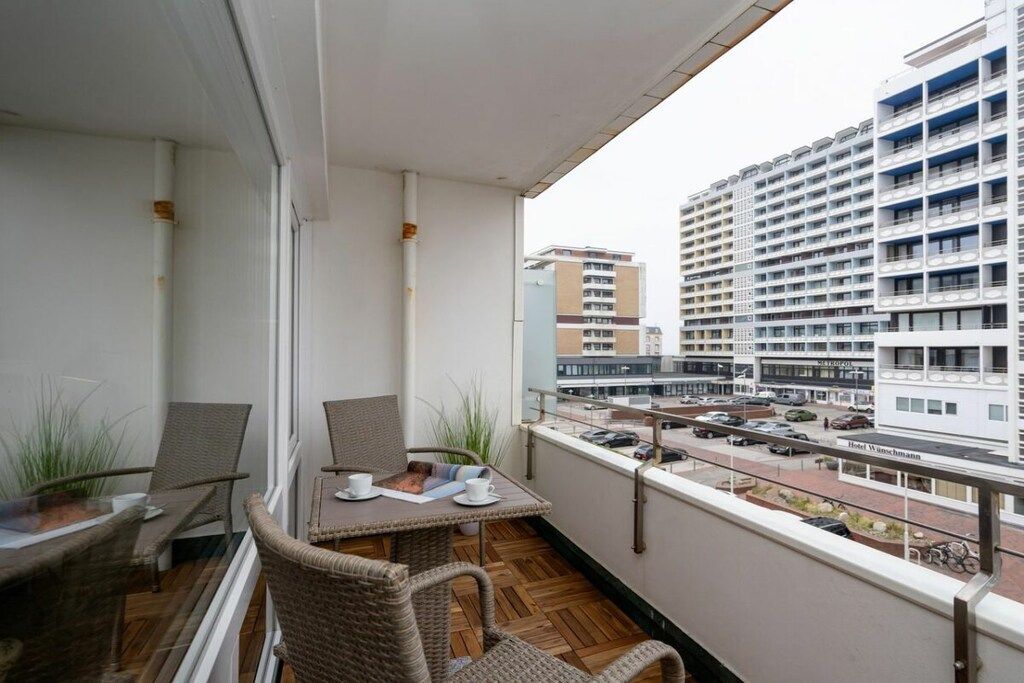 A balcony with wicker furniture, a table, and chairs.