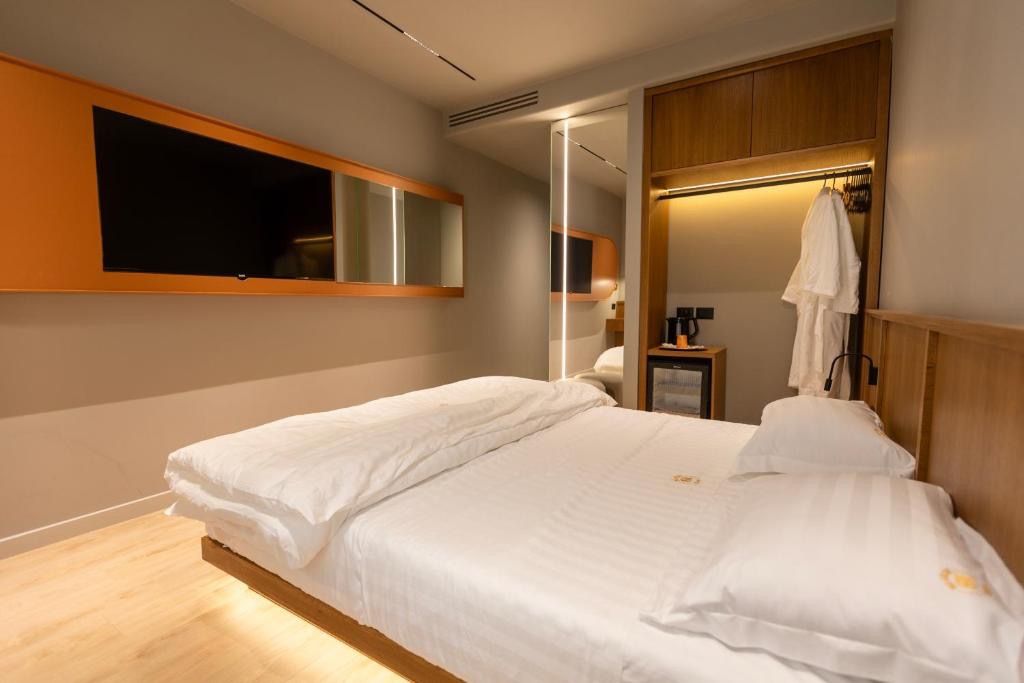 Una habitación de hotel con una cama, un televisor montado en la pared y un armario de madera.