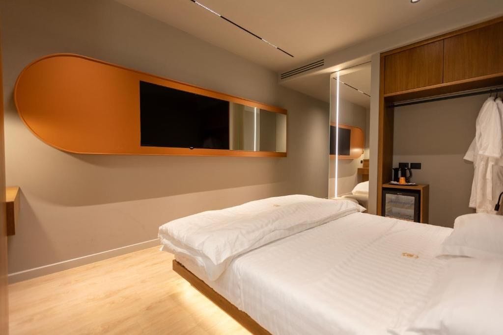 Un dormitorio moderno con una cama grande, un armario empotrado y un espejo fijado a la pared.
