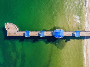 Vue aérienne d’une jetée dotée d’une plateforme en bois et de toiles d’auvent bleues.