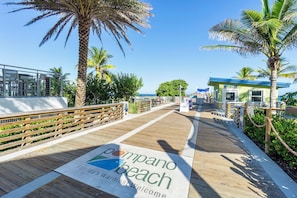 Ein hölzerner Steg mit einem Schild, auf dem steht: 'Pompano Beach, Floridas herzlichste Begrüßung'.