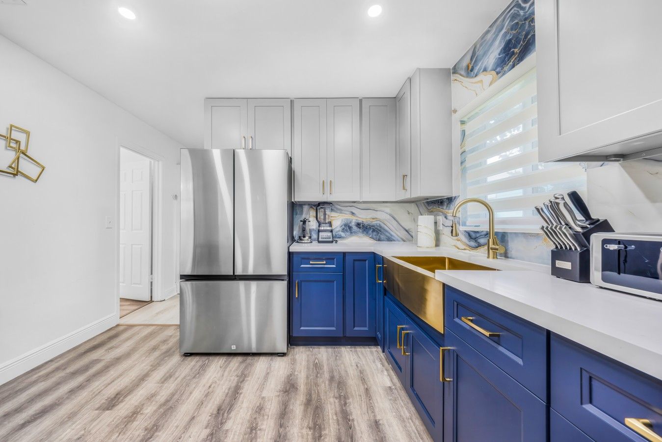 A modern kitchen with stainless steel appliances, a marble backsplash, and blue cabinetry.