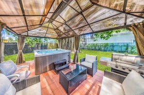 An outdoor patio with a hot tub, seating area, and a grill. - Miami Tree House - Renovated Single-Story Oasis with a Private Jacuzzi and Fenced Yard in Miami (Miami)