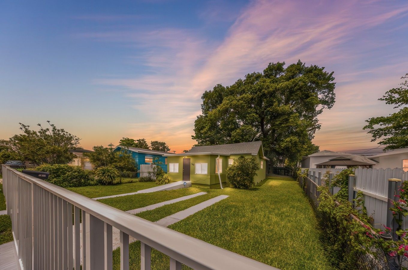 A residential backyard with a lawn, a wooden deck, and a large tree.