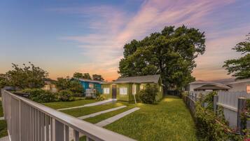 A residential backyard with a lawn, a wooden deck, and a large tree.