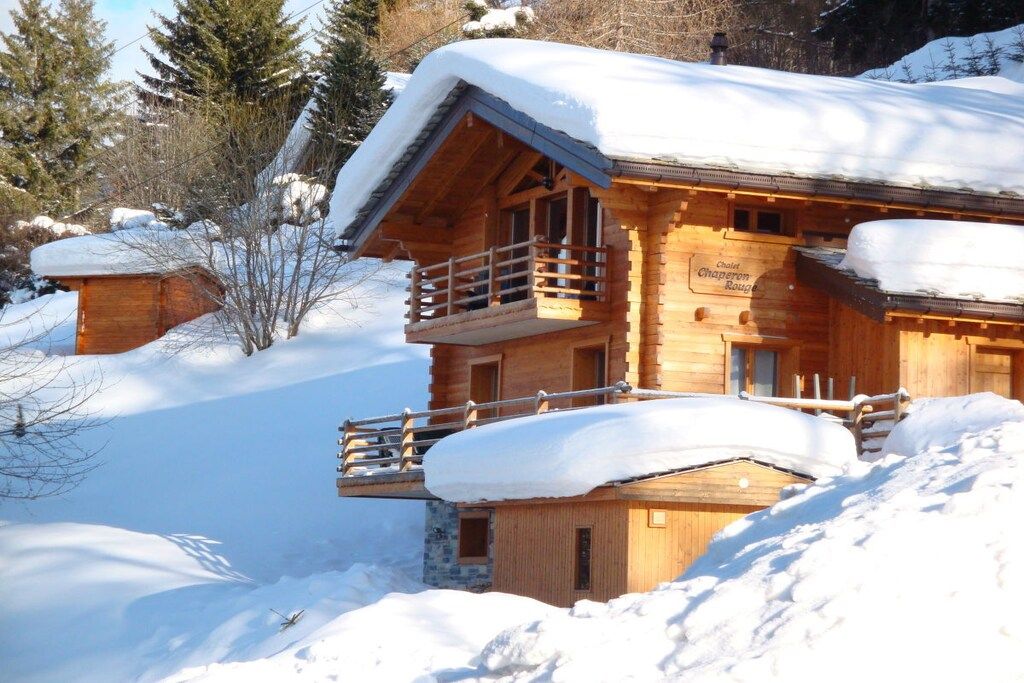 Een houten chalet met balkon, omringd door sneeuw.