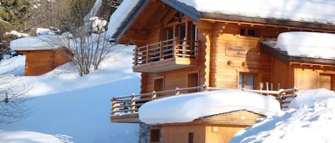 Een houten chalet met balkon, omringd door sneeuw.