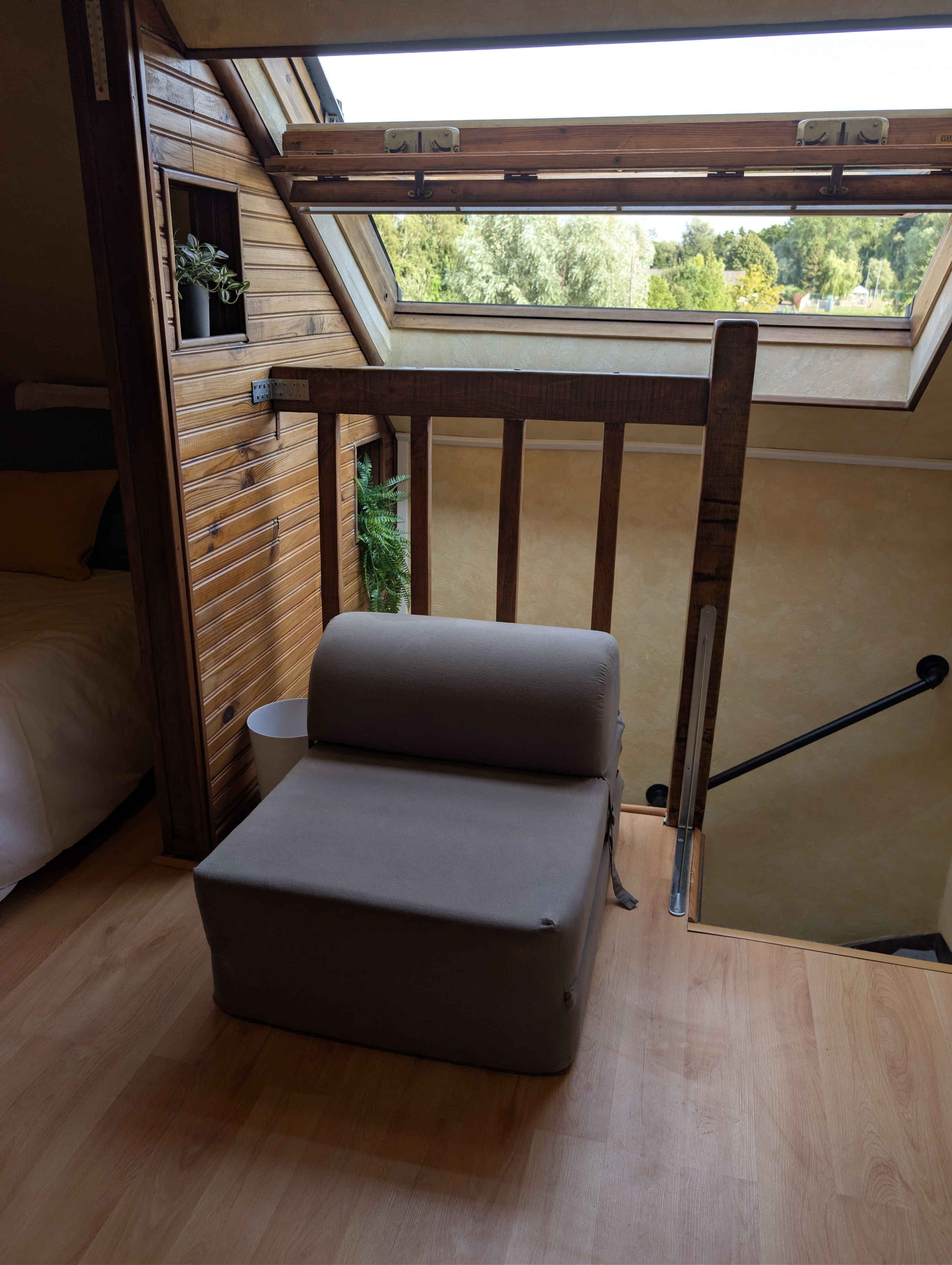 A compact room with a skylight, a bed, a small table, and a bench.