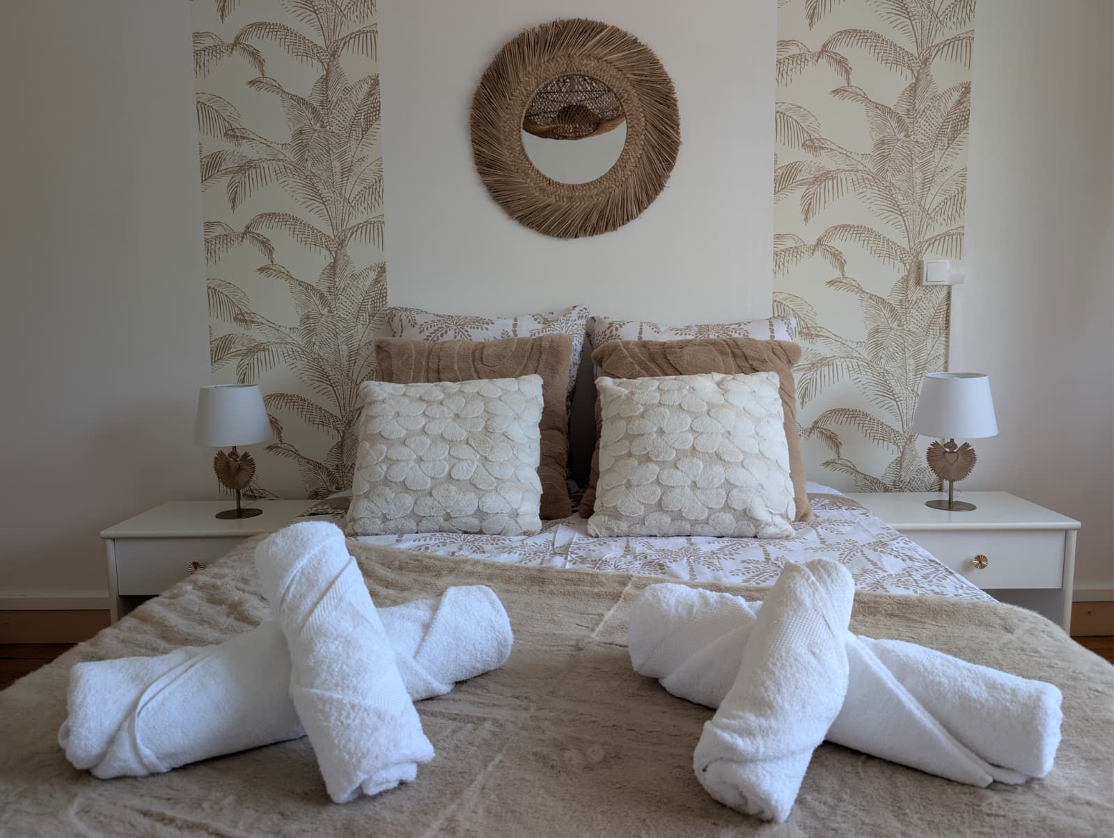 A neatly made bed with two pillows, a wall-mounted mirror, and two bedside tables with lamps.