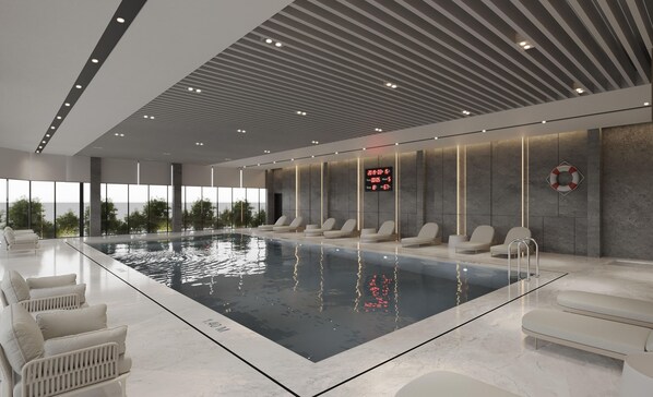 Una piscina interior moderna con sillones de descanso y una pantalla digital.