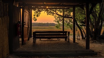Una panca di legno sotto un riparo con vista su un tramonto su un campo.