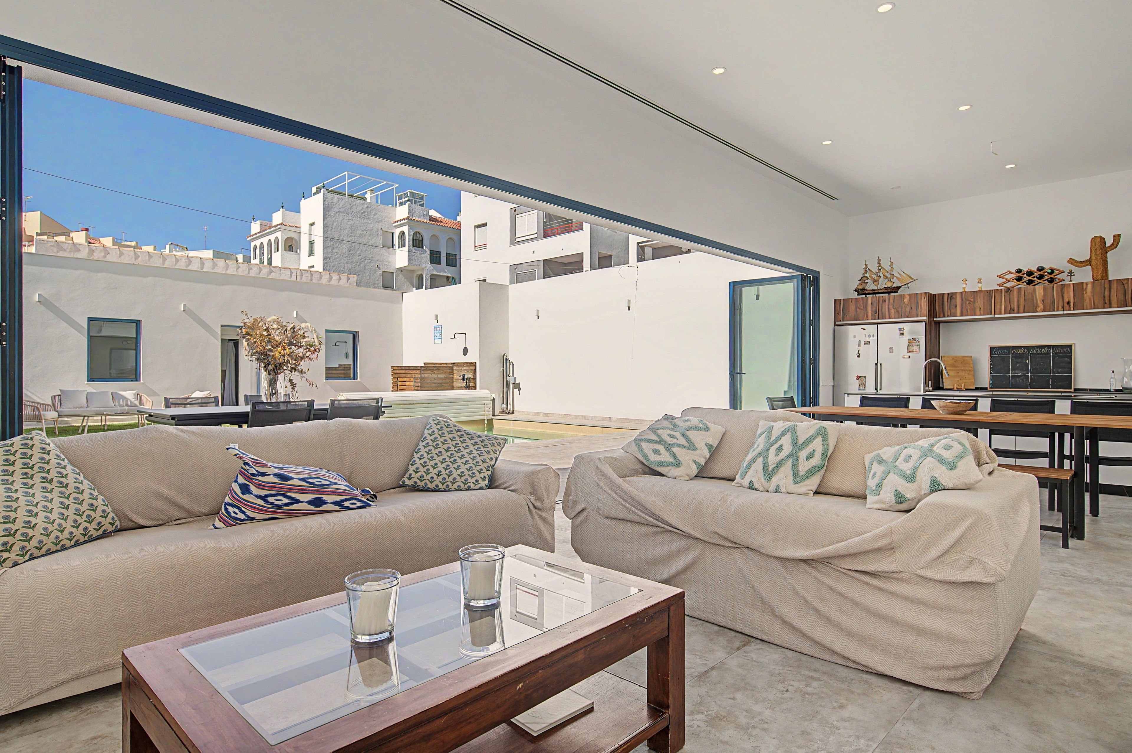 A modern living room with a sofa set, a glass coffee table, and a view of the cityscape through large windows.