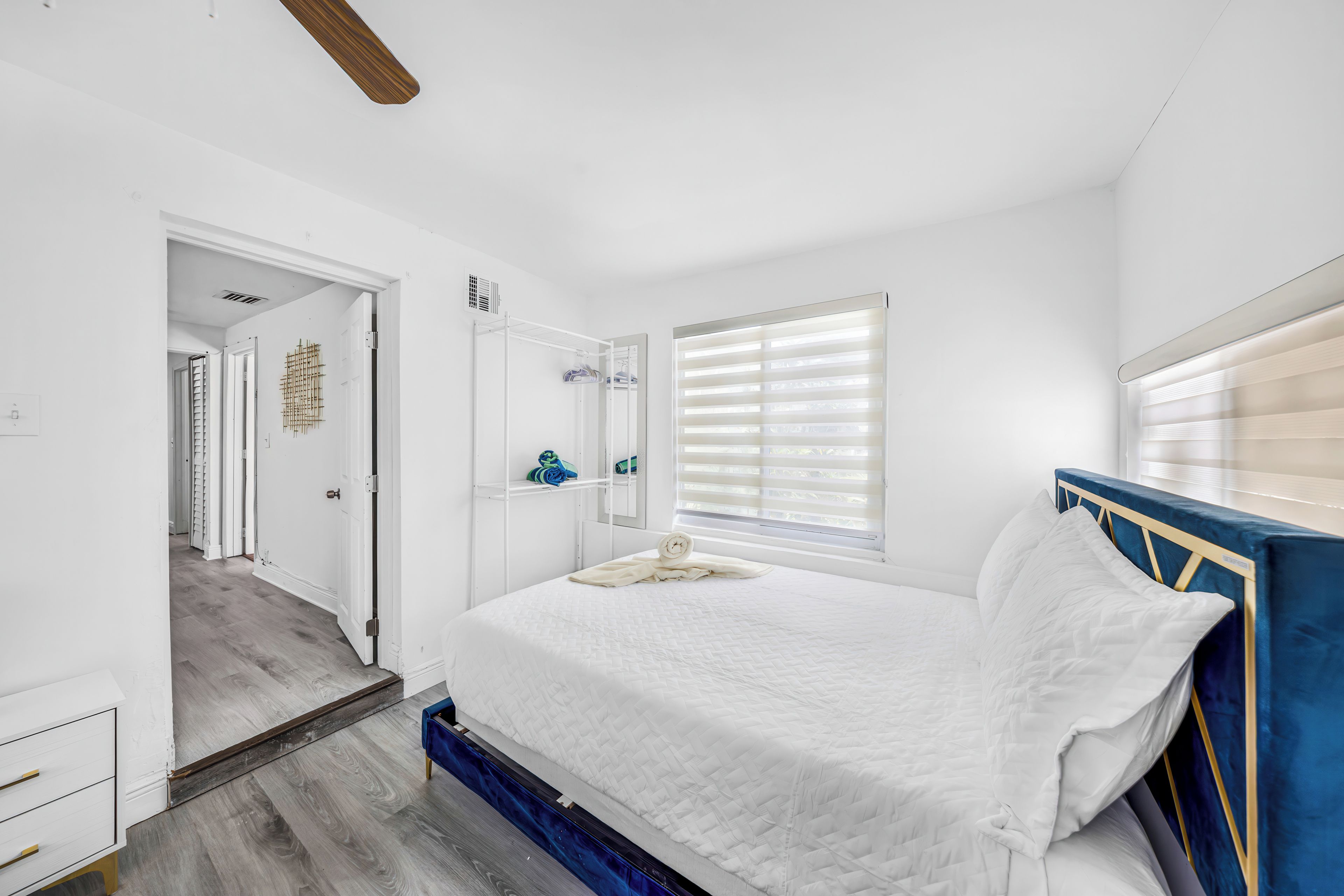 Un dormitorio con cama, cómoda, espejo y ventana con persianas.