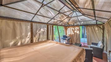 A tented accommodation with a bed, a table, and a chair.