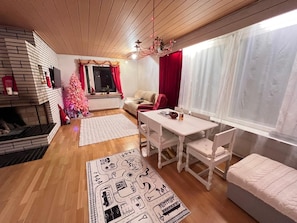 En hyggelig stue med pejs, spisebord og sofa.
