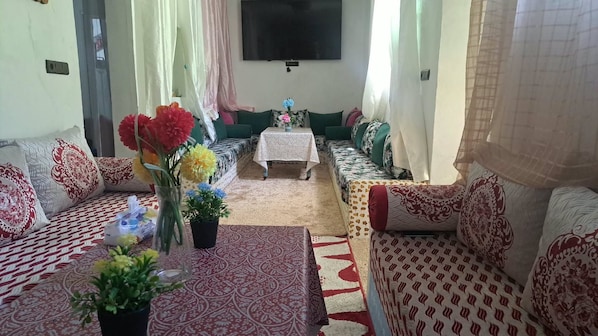 A living room with a sofa set, a coffee table, and a TV mounted on the wall.