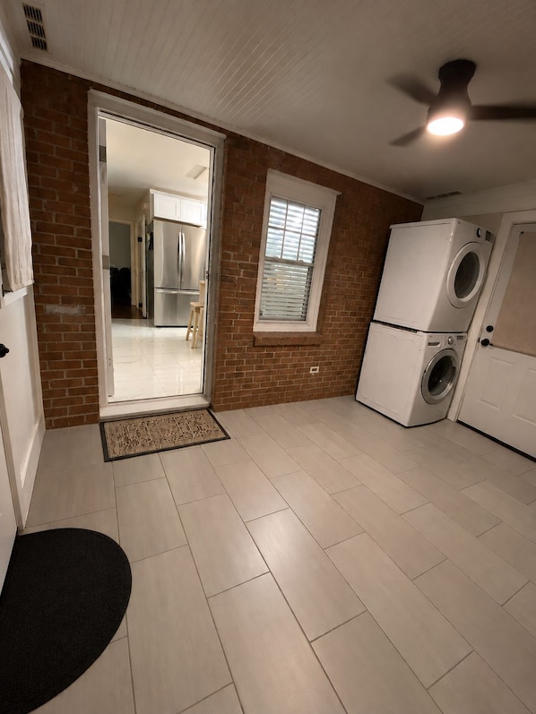 Un lavadero con ventilador de techo, una ventana y una puerta que da a una cocina.