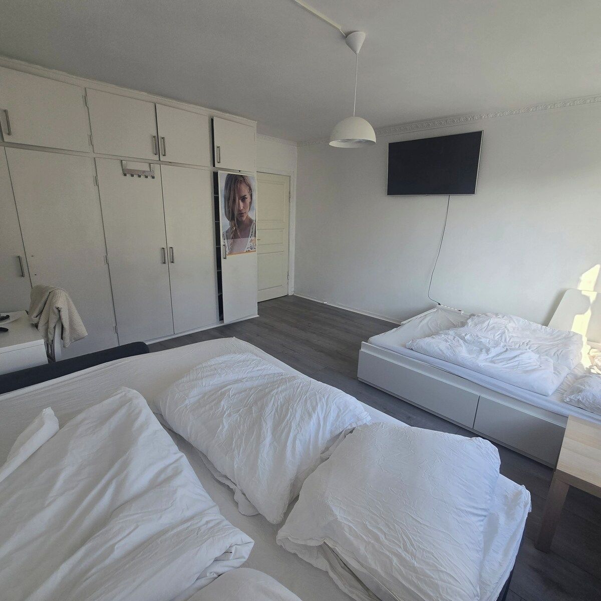 Habitació d'hotel amb dos llits, un armari, una televisió i una taula de nit.