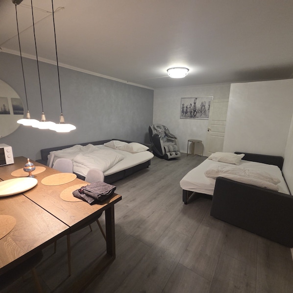 A bedroom with two beds, a desk, a massage chair, and a wall-mounted artwork.