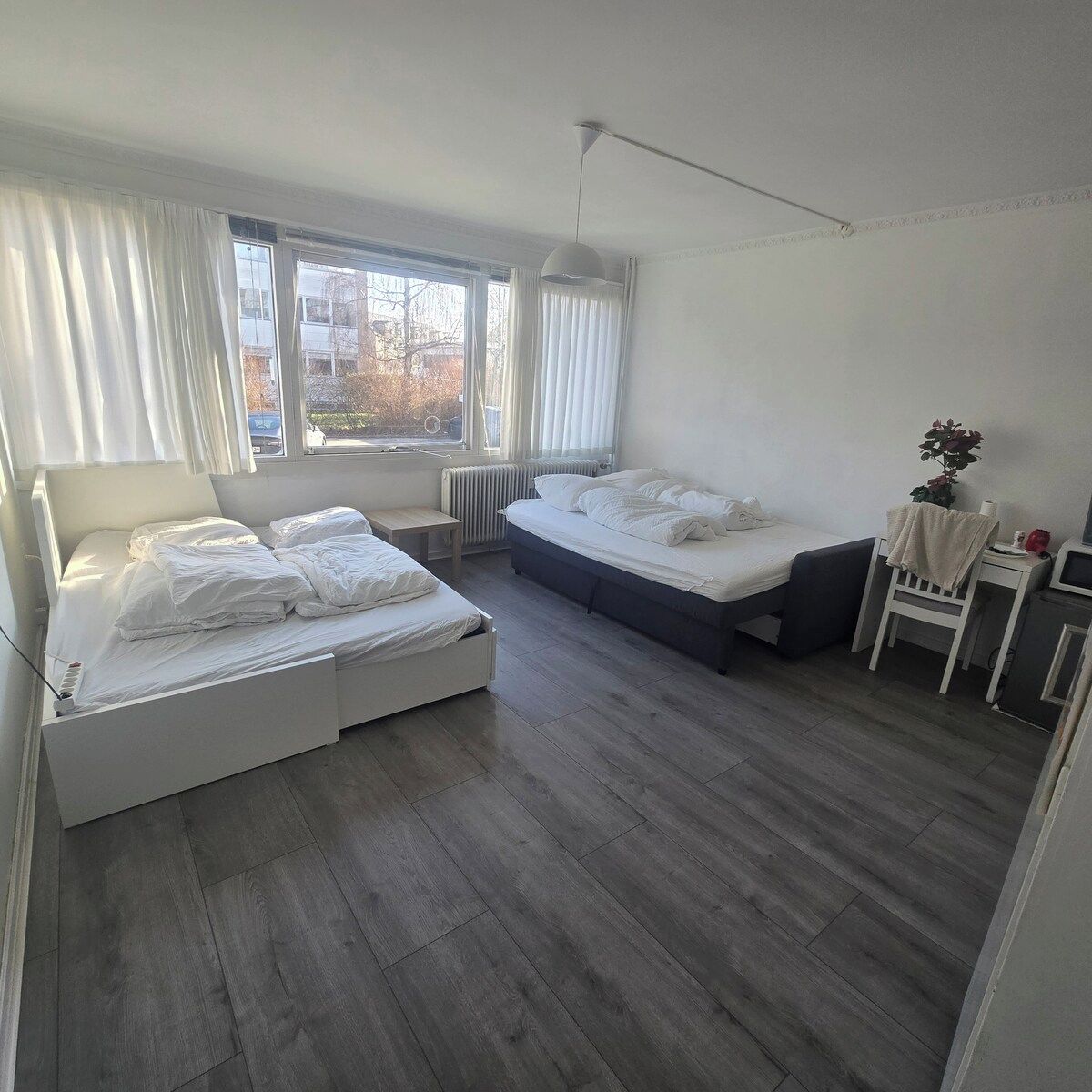 Een moderne slaapkamer met twee bedden, een bureau en een radiator.