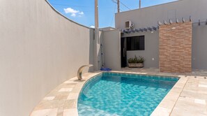 A swimming pool with a checkered tile pattern, a water feature, and a potted plant. - House with Swimming Pool and Barbecue in Jd. Universal (Colina)