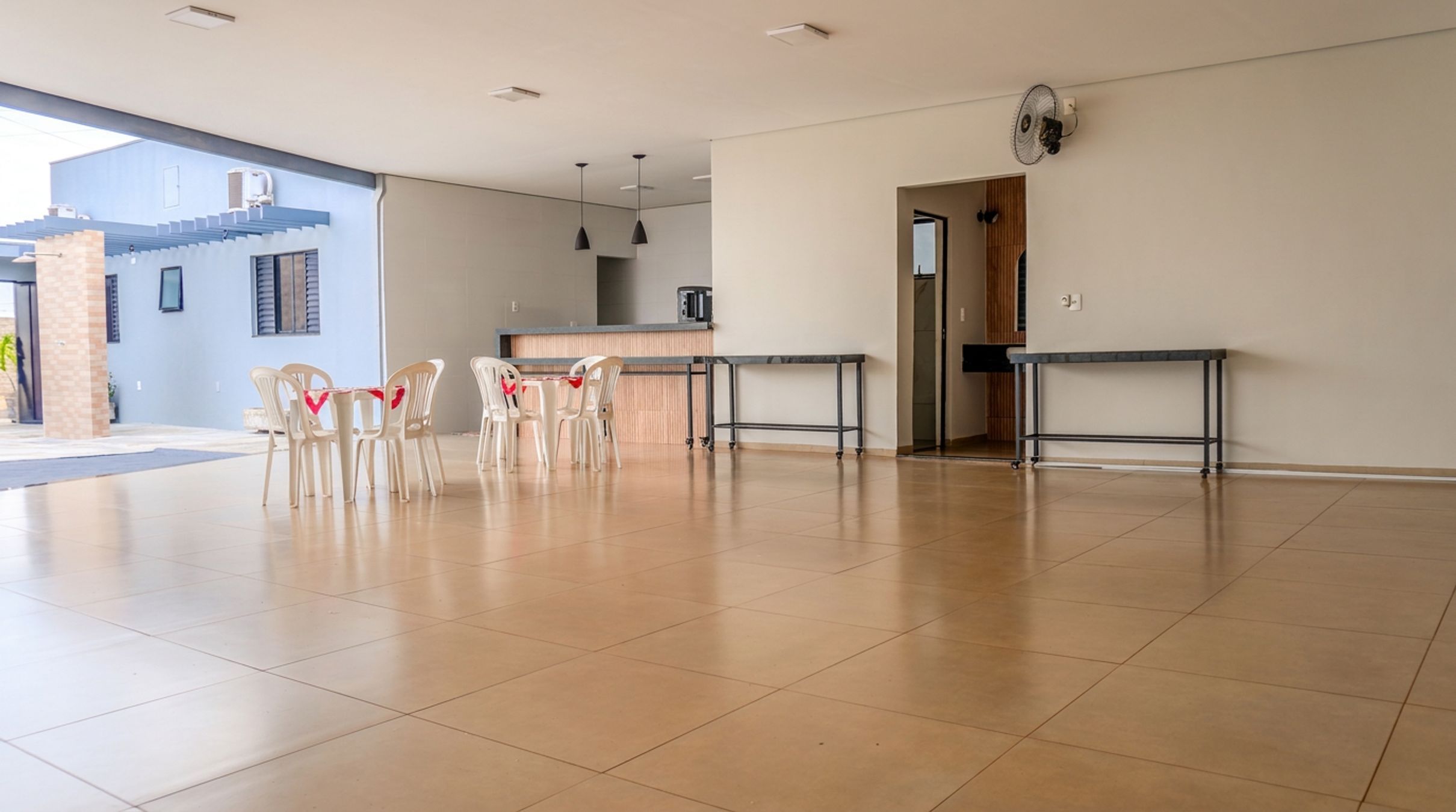 A spacious indoor area with a reception desk, a kitchen area, and a seating area with chairs.