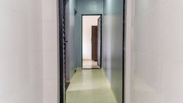 A narrow hallway with a tiled floor leading to a room with a door.