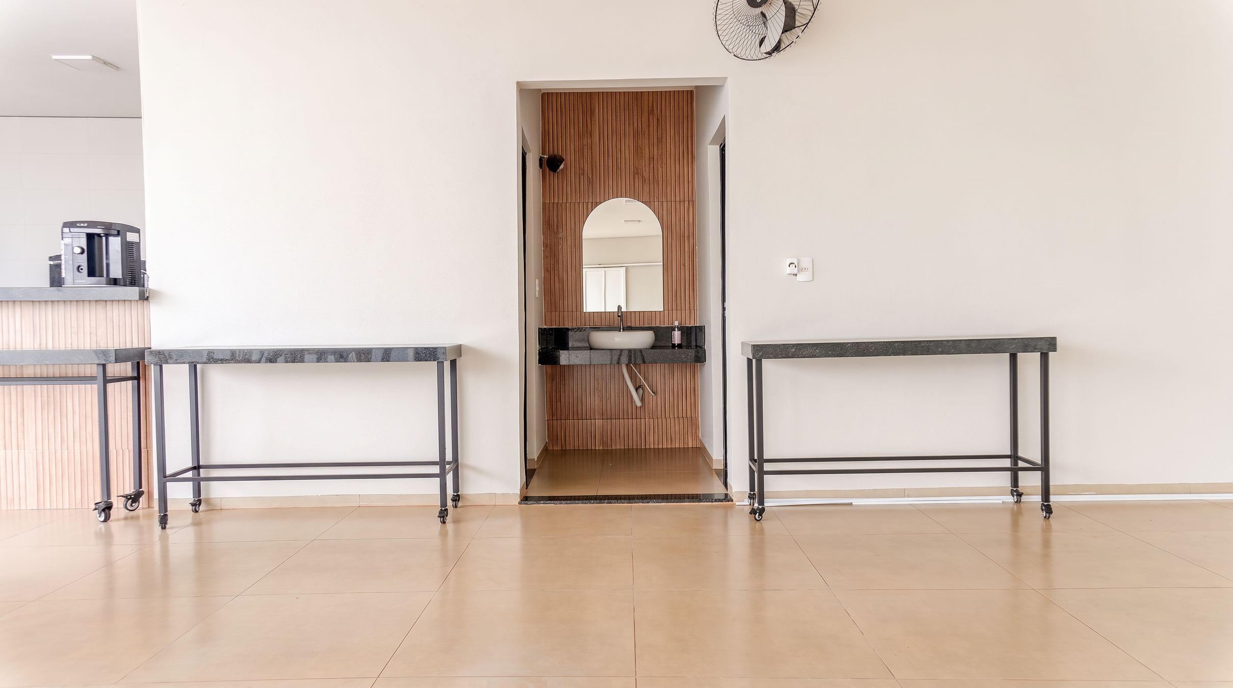 A modern kitchen with two black metal tables, a wooden door, and a white wall.