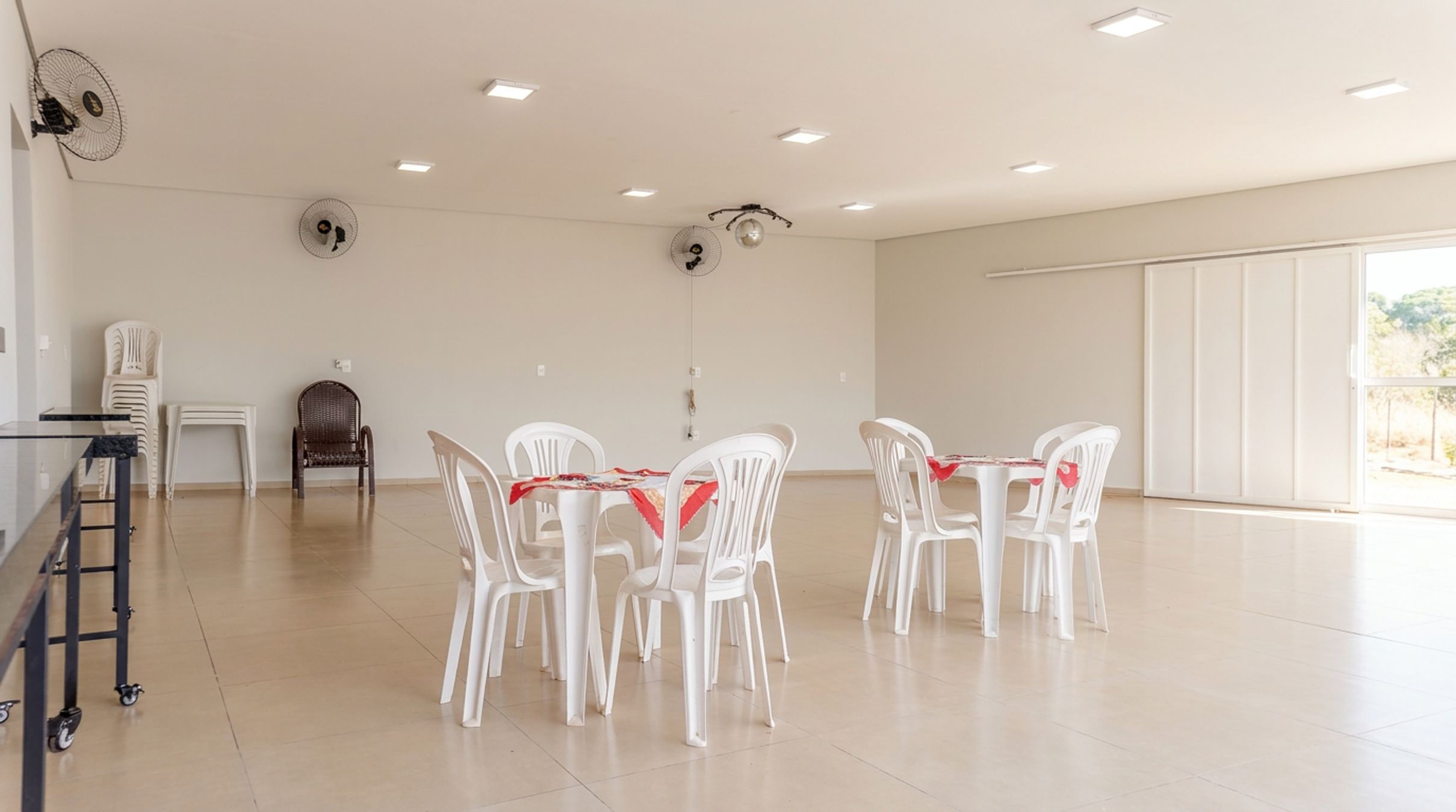 A spacious room with a high ceiling, recessed lighting, and a large window.