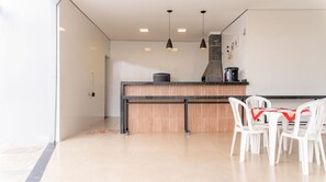 A modern kitchen with a central island, pendant lighting, and a dining area with white chairs. - House with Swimming Pool and Barbecue in Jd. Universal (Colina)