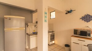 Eine kompakte Küche mit Kühlschrank, Backofen, Mikrowelle und einer kleinen Arbeitsfläche.