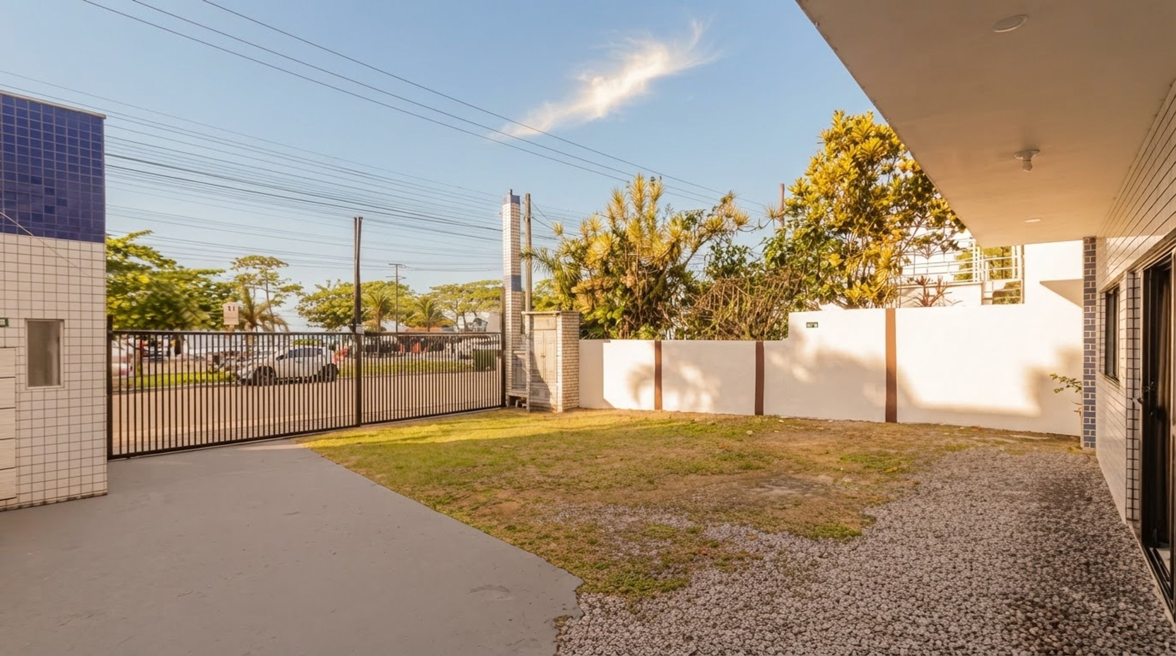 A residential property with a paved driveway, a fenced yard, and a white exterior wall.