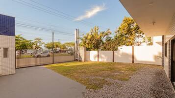 A residential property with a paved driveway, a fenced yard, and a white exterior wall.