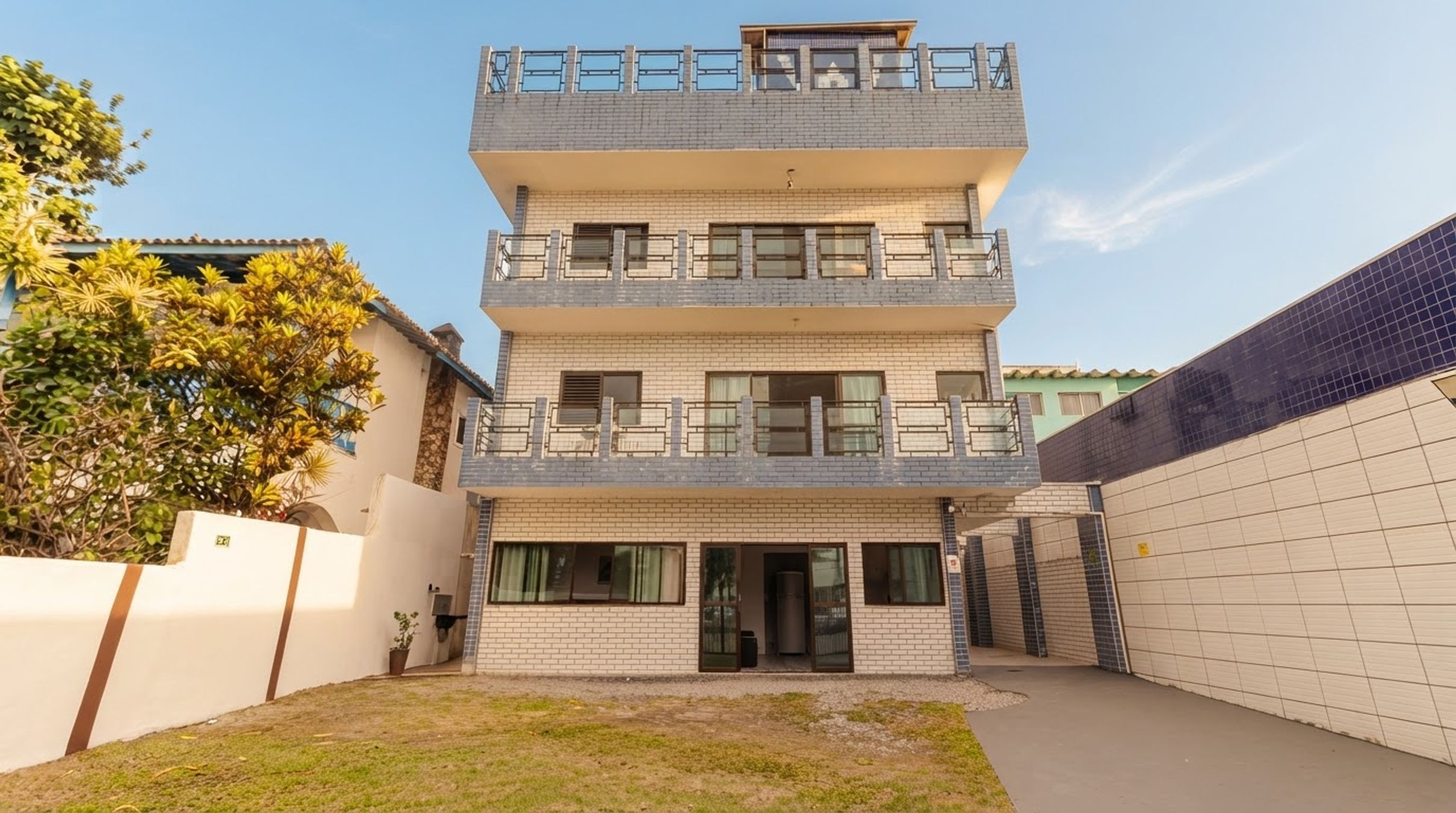 A multi-story residential building with a flat roof, balconies, and a gated entrance.