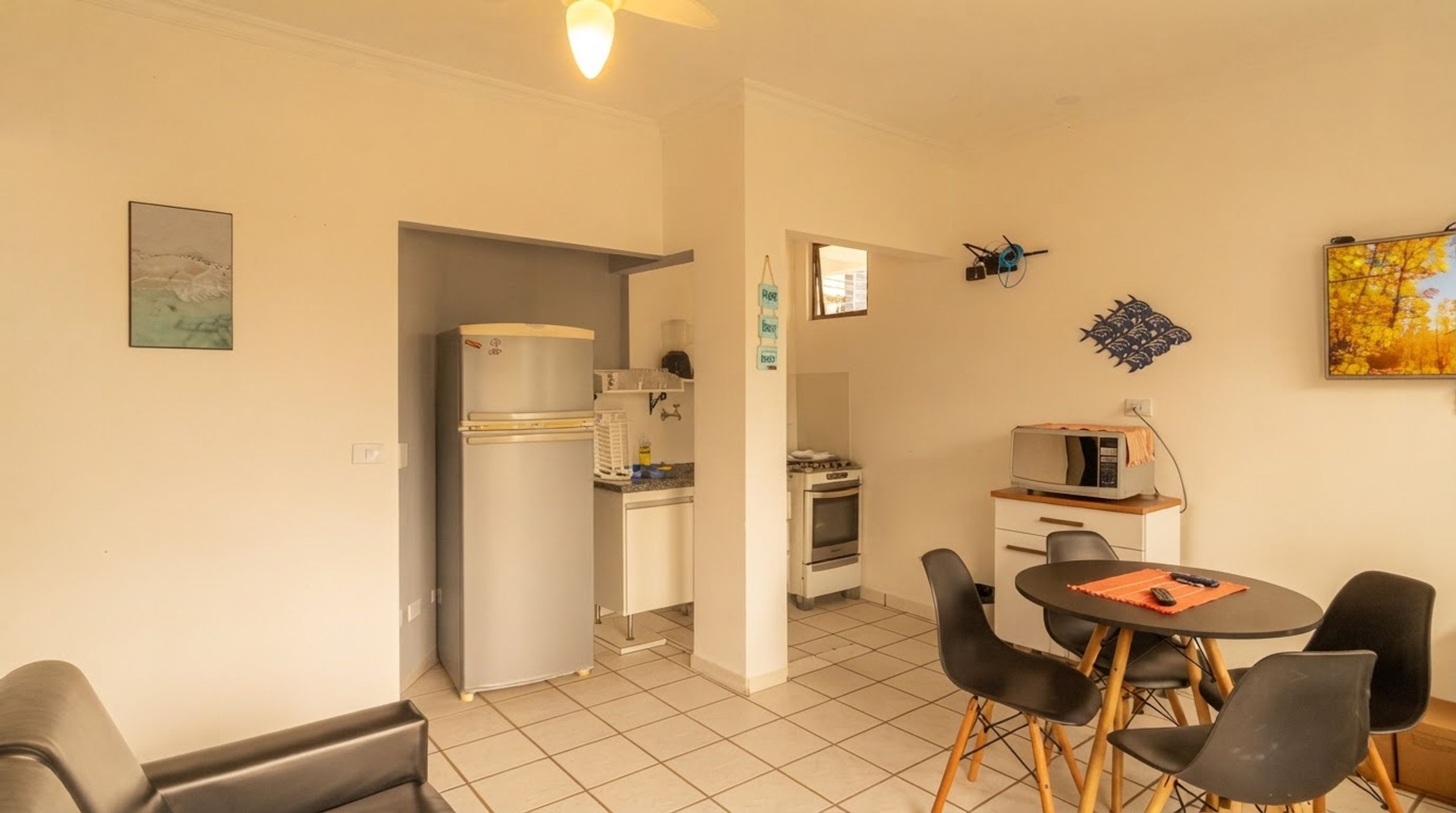 A compact living space with a kitchenette, a dining area with a table and chairs, and a small TV.
