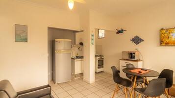 A compact living space with a kitchenette, a dining area with a table and chairs, and a small TV.