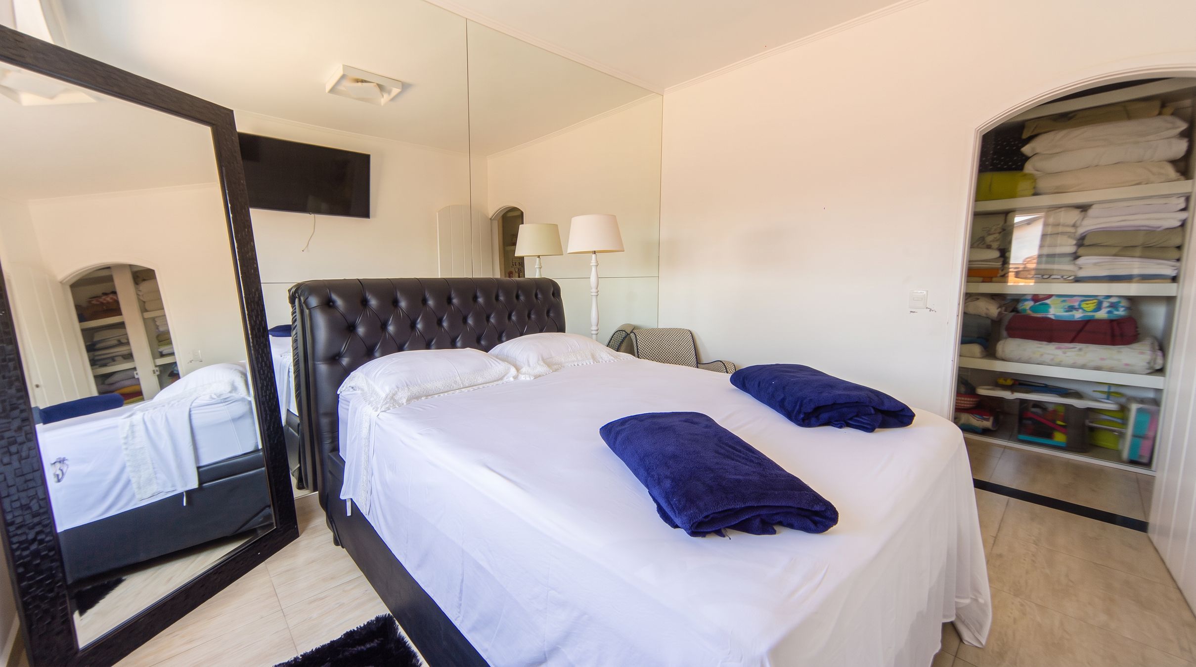 A hotel room with a bed, a mirror, a wardrobe, and a lamp.