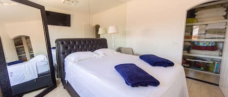 A hotel room with a bed, a mirror, a wardrobe, and a lamp.