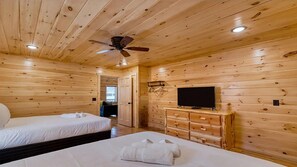 A wooden cabin room with two beds, a ceiling fan, a TV, and a dresser. - Chill N in the Smokies 2-Bdrm & Loft, Hot Tub, Game Tables & Resort Pool (Gatlinburg)