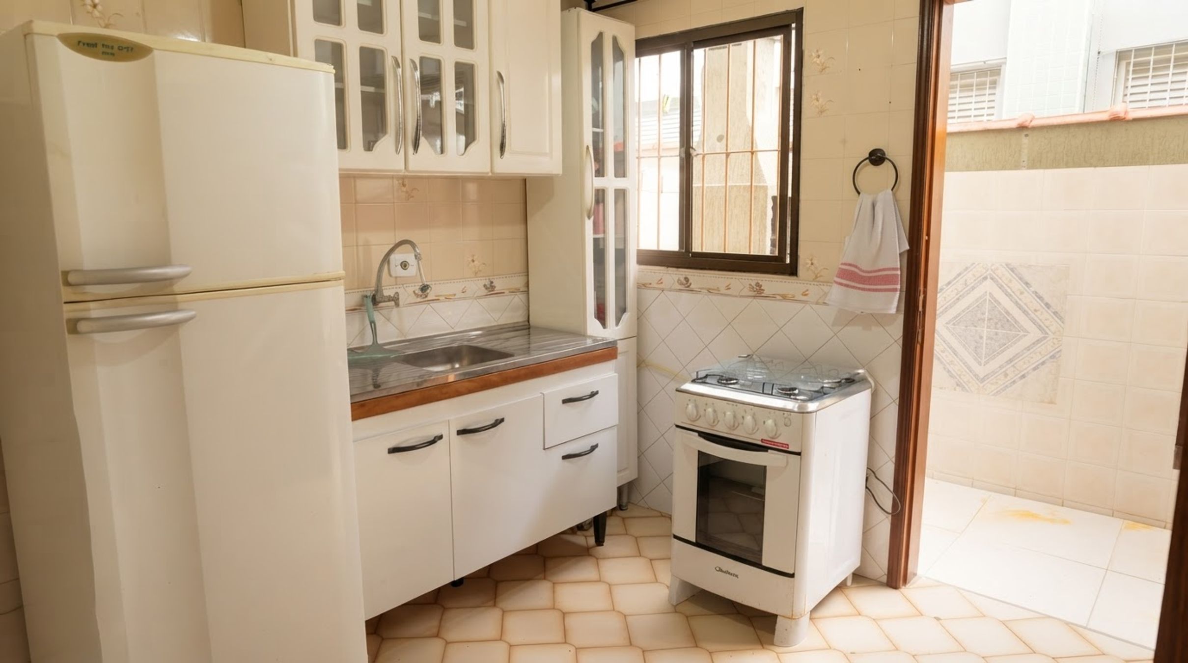 A compact kitchen with white cabinetry, a built-in oven, and a window above the sink.